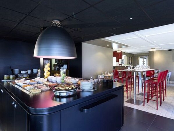 Una cocina moderna con una isla central, sillas rojas y un área de comedor al fondo.