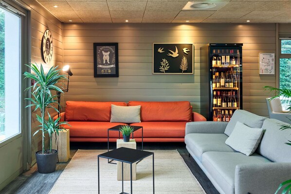 Un salón moderno con un sofá rojo, un sofá gris, una mesa de centro negra y una estantería para vinos.