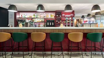 Uma área de bar com balcão, banquetas e prateleiras cheias de garrafas.
