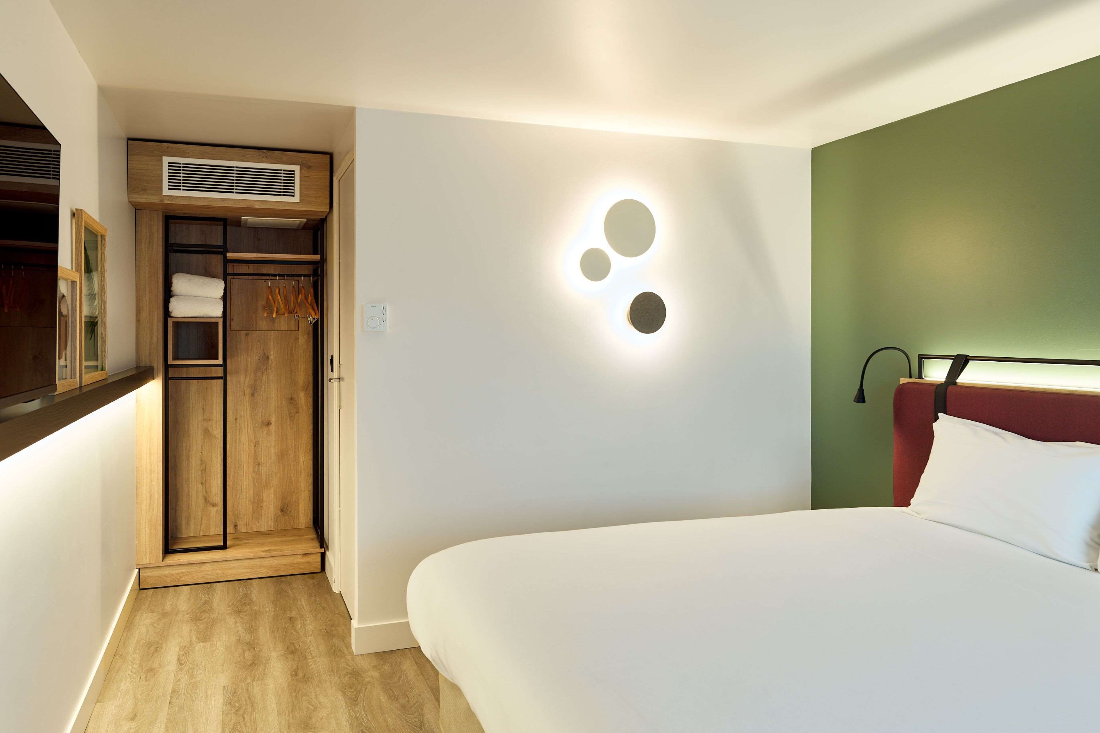 Un dormitorio con cama, armario, espejo e iluminación empotrada.