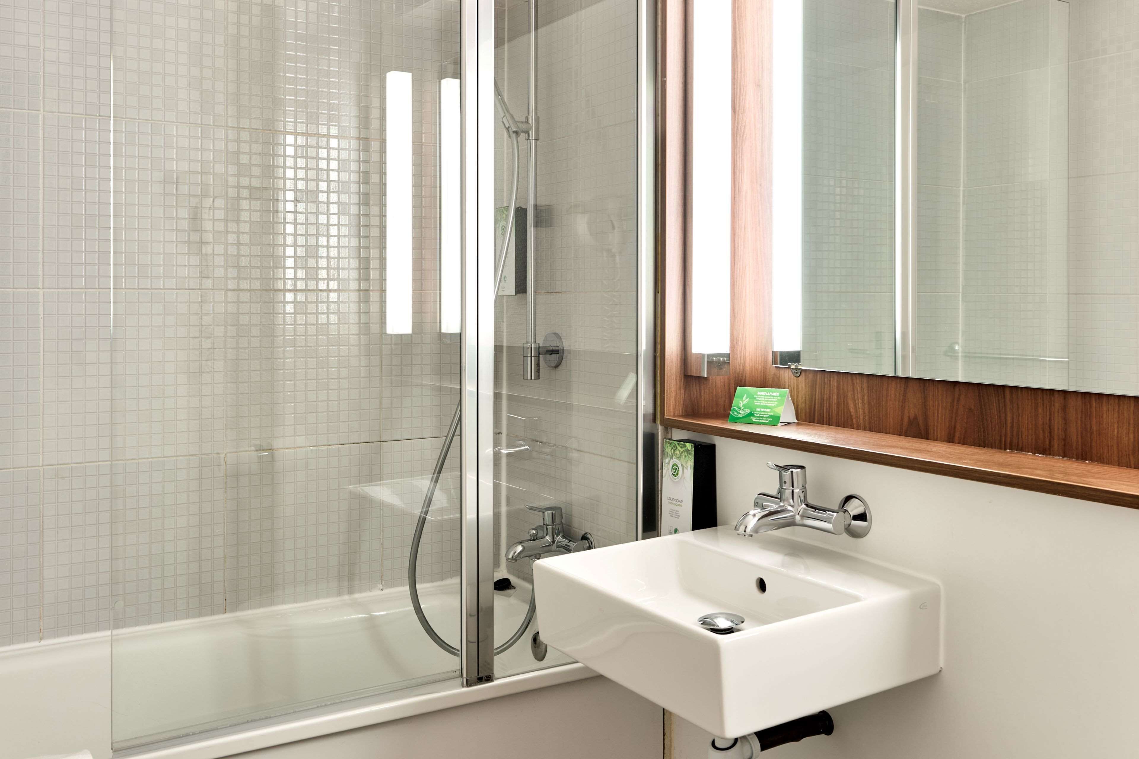 A modern bathroom with a glass-enclosed shower, a white sink, and a wooden shelf.