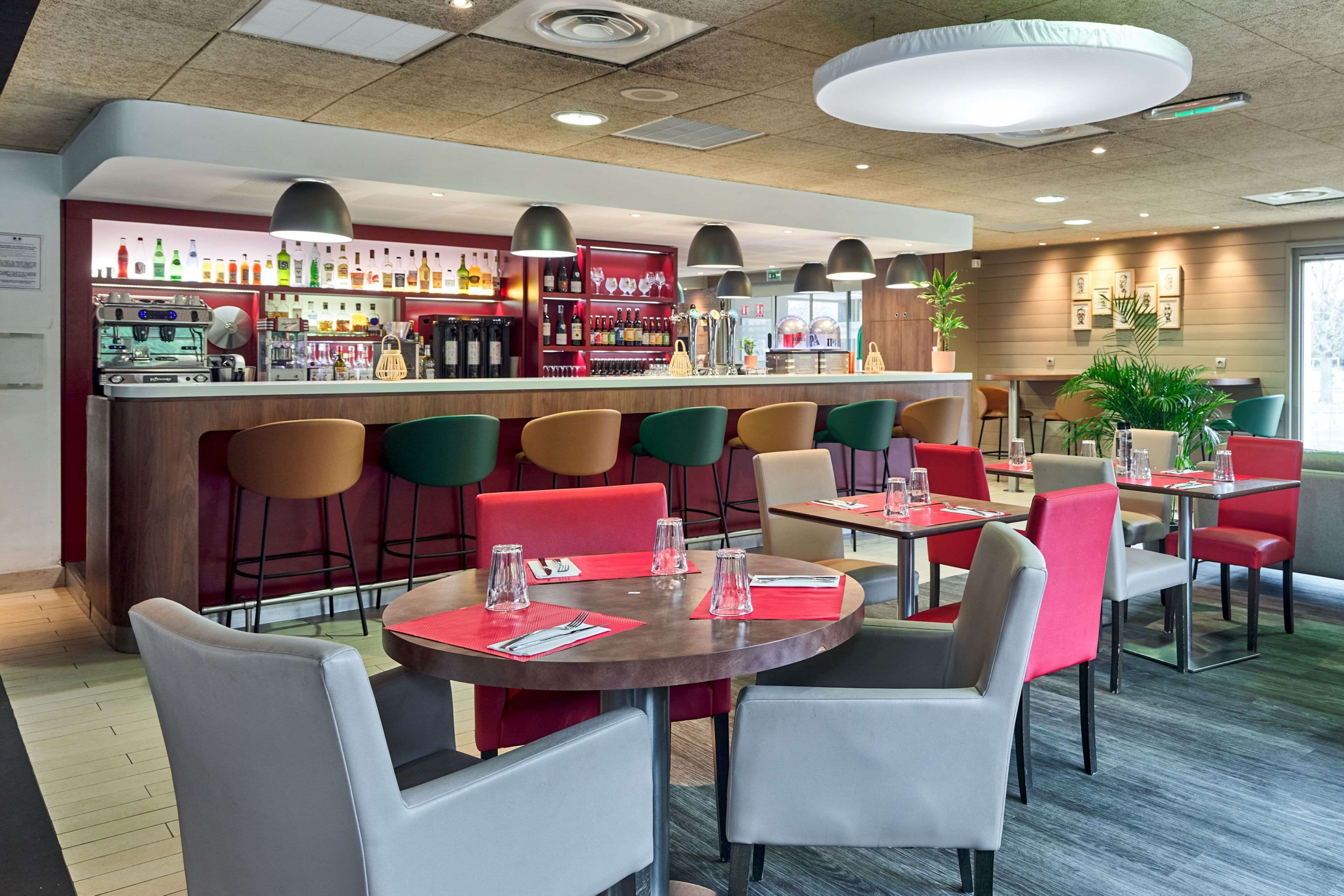 Un restaurante moderno con zona de bar, diversas opciones de asientos y una amplia variedad de bebidas.