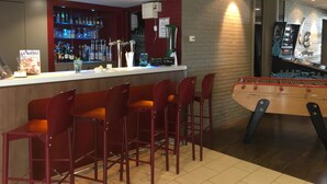 A bar area with stools, a foosball table, and a well-stocked bar counter. - Campanile PRIME - Saint-Quentin-en-Yvelines (Montigny-le-Bretonneux)