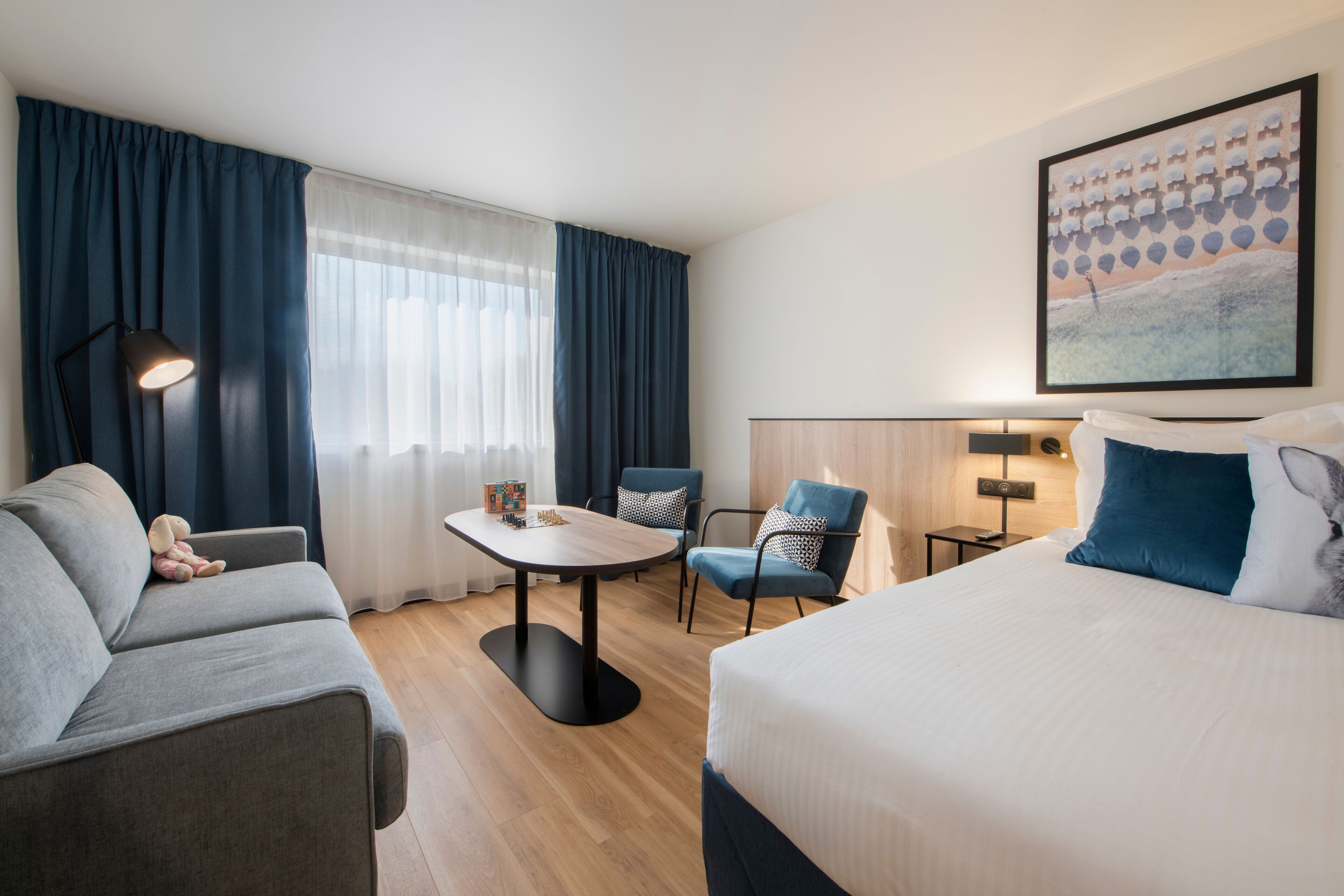A hotel room with a bed, a sofa, a dining table, and two chairs.
