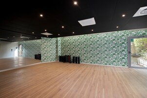 Una habitación amplia con suelo de madera y papel tapiz estampado con hojas verdes.