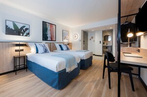 Una habitación de hotel moderna con dos camas, un escritorio y una silla.