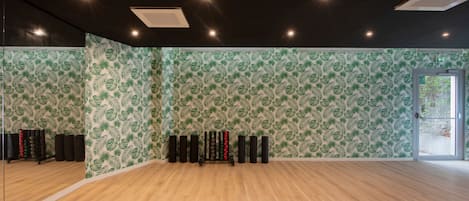 A gym with mirrored walls, wooden flooring, and a mirrored door.