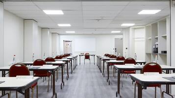 Ein Konferenzraum mit Tischen, Stühlen, einer Tafel und einem Banner.