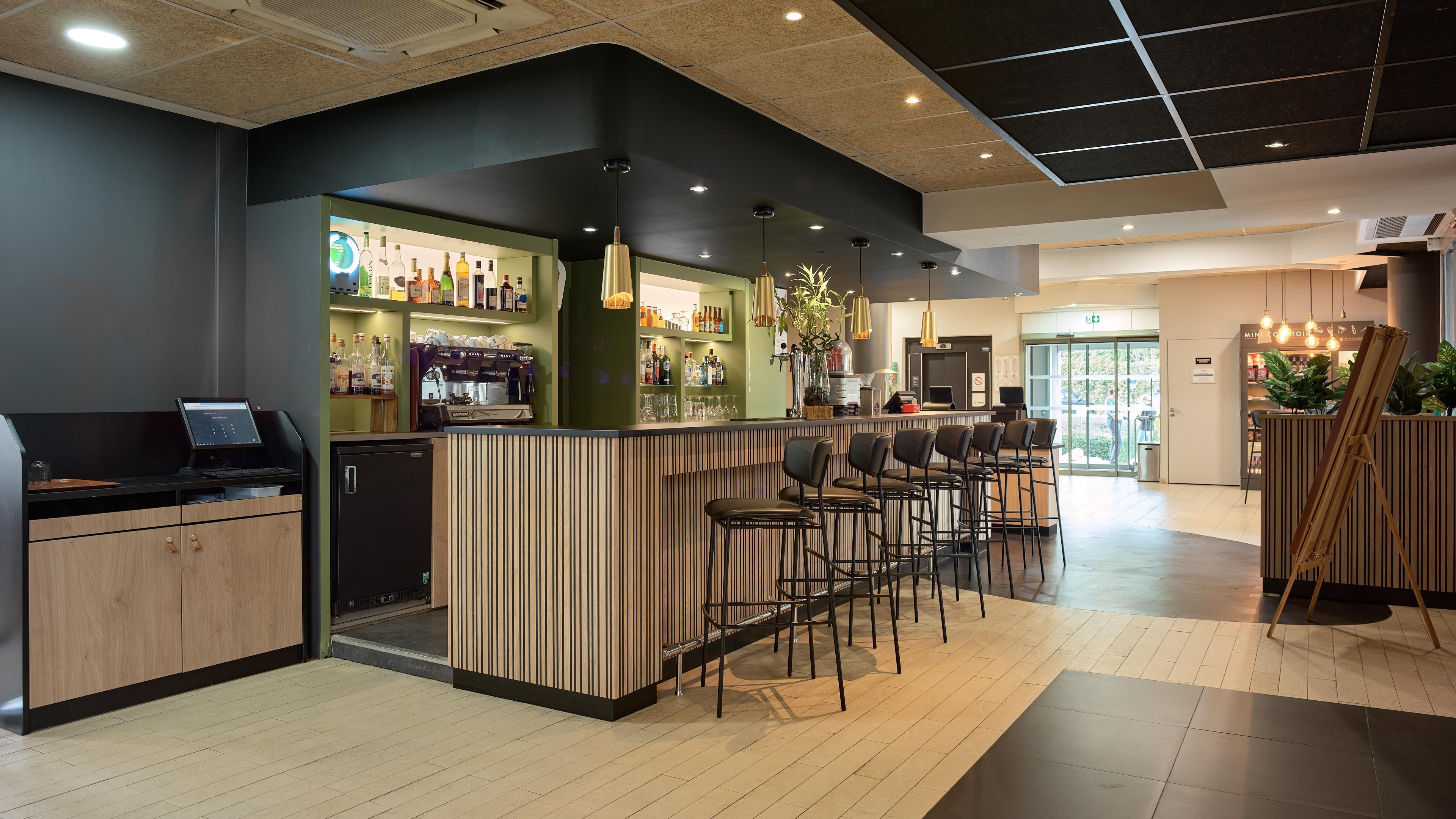 A modern bar area with a counter, seating, and a coffee machine.