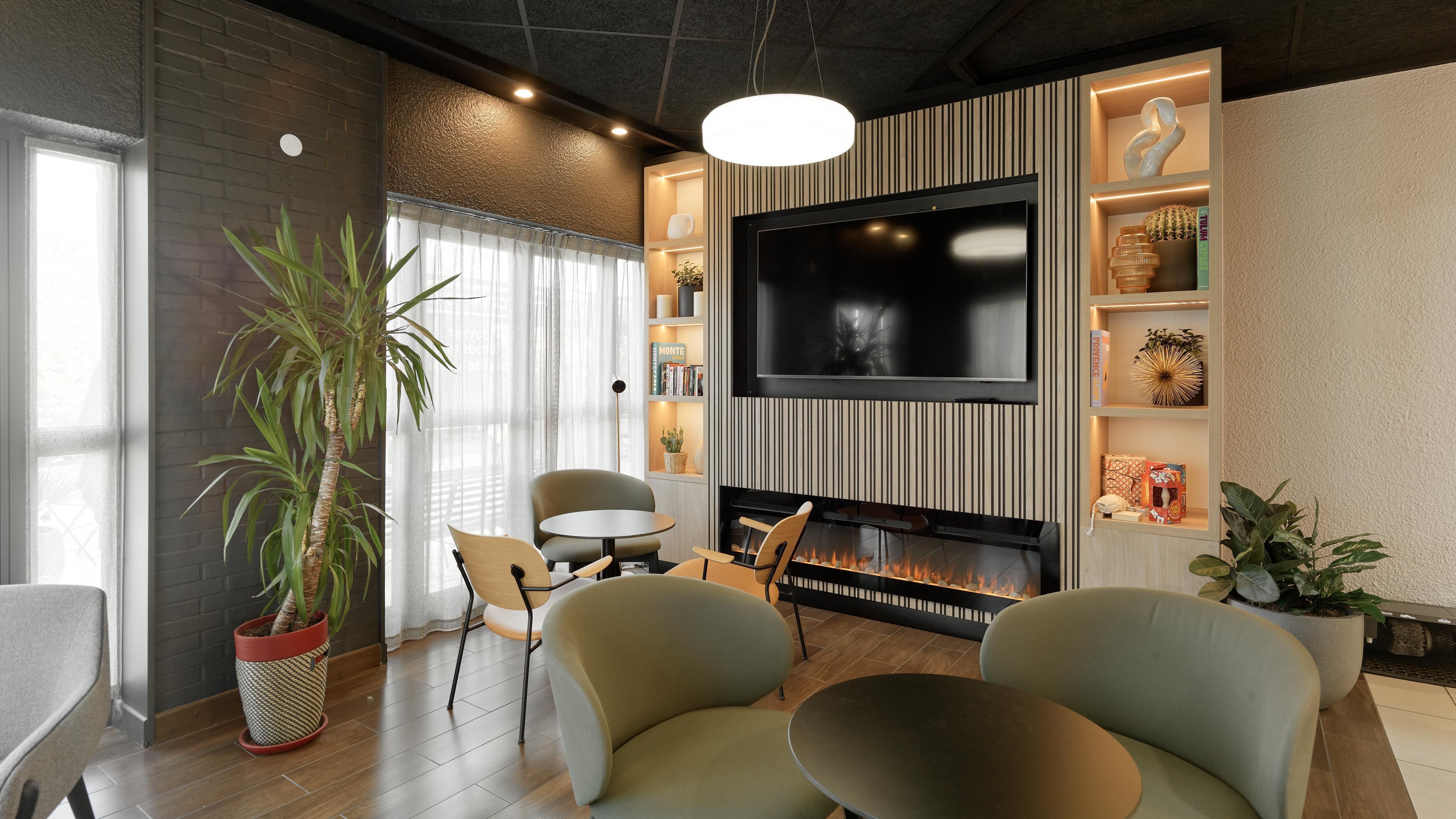 Un salon moderne doté d’une cheminée, d’un téléviseur à écran plat et de sièges confortables.