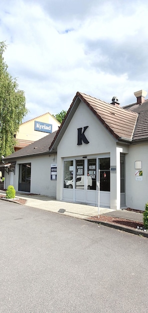 A building with a large 'K' sign, a welcoming sign, and a 'Kyriad' sign in the background.