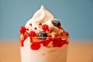 Ein Dessert im Glas mit Schlagsahne, Beeren und Granola.