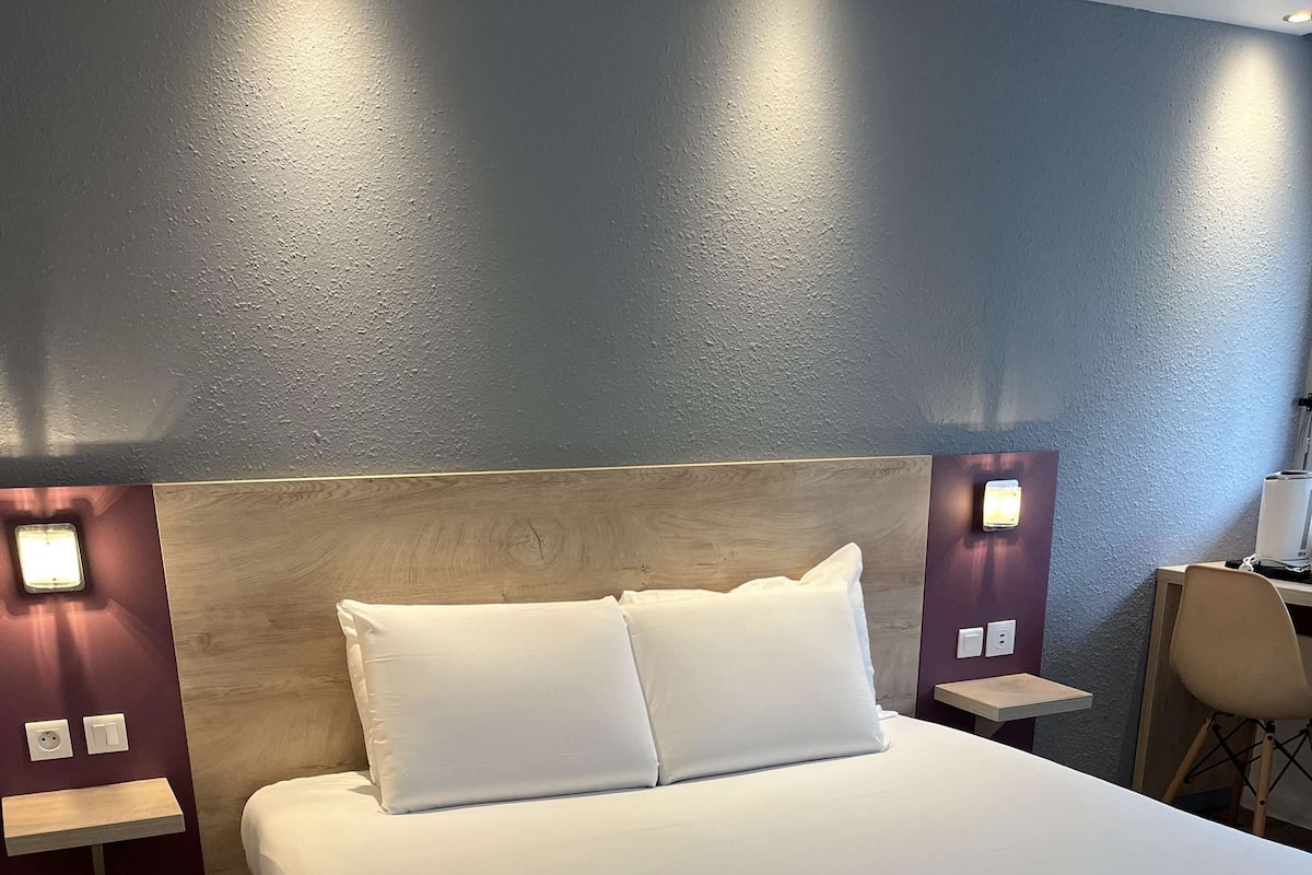 En pænt redt seng med hvide sengetøj i et hotelværelse.