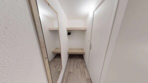 Ein schmaler Flur mit weißen Wänden und Holzböden. An der Wand sind zwei Holzregale übereinander angebracht.