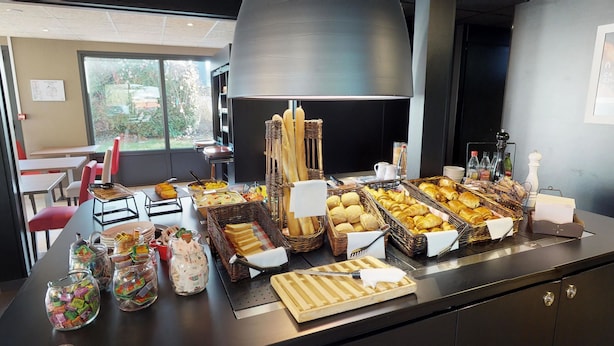 Uma mesa de buffet com diversos pães, bolos e acompanhamentos.