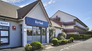 Un hôtel appelé « Kyriad », doté d’une réception, d’un panneau indiquant la présence d’un restaurant et d’un parking.
