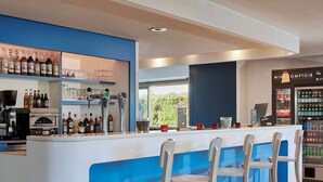 Un espace bar aux couleurs bleu et blanc, avec des tabourets de bar, des étagères remplies de bouteilles et un mini-réfrigérateur.