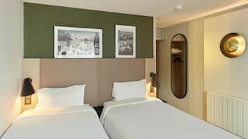 A hotel room with two beds, a large mirror, and two framed pictures on the wall.