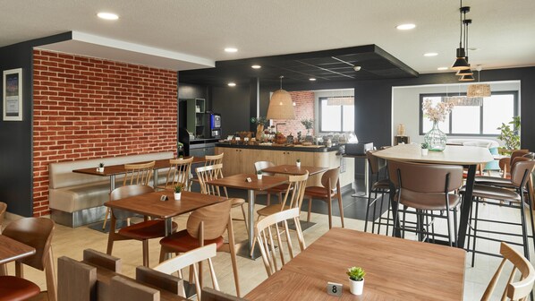 Un restaurant moderne avec des murs en briques, des tables et des chaises en bois, et un espace bar.