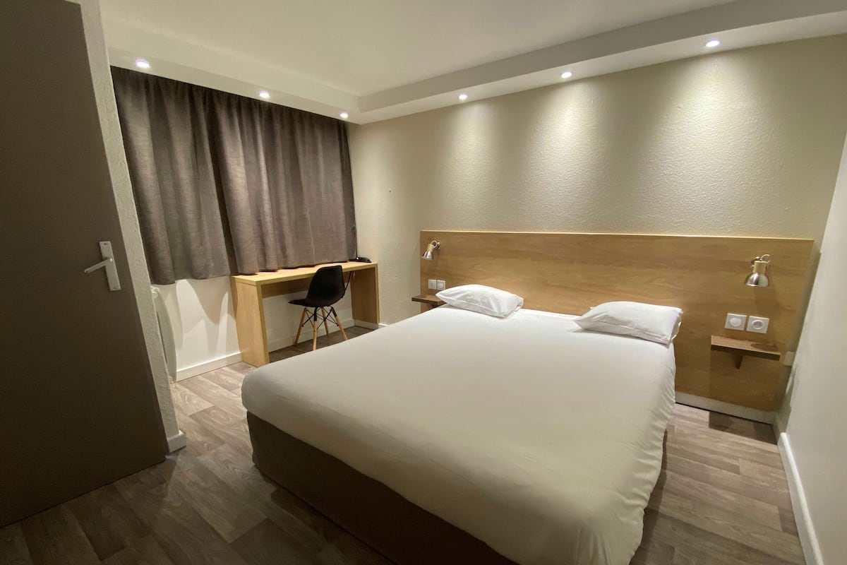 Una habitación de hotel con una cama grande, un escritorio y una silla.