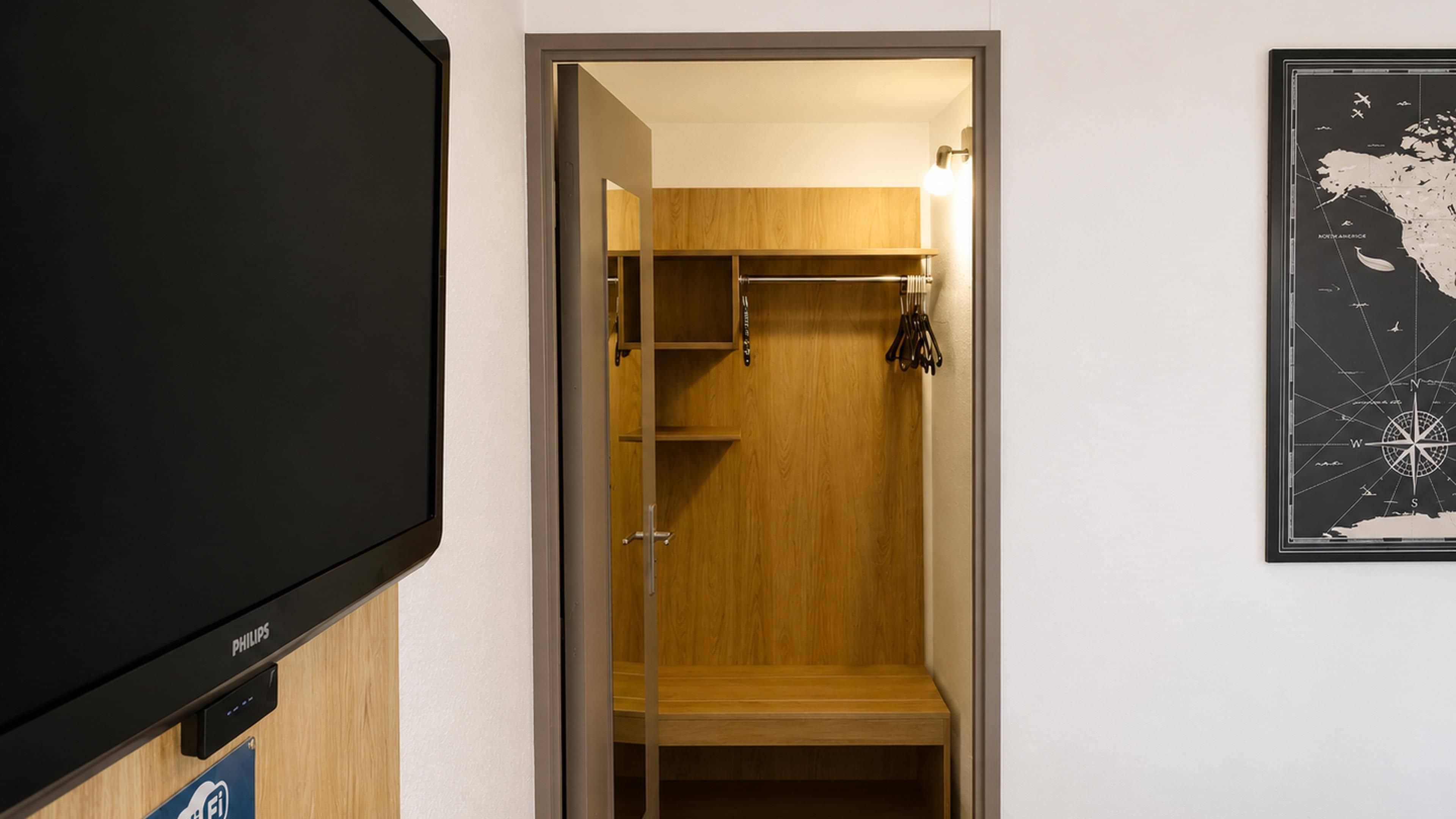 Una habitación con televisión, un armario de madera y un mapa colgado en la pared.