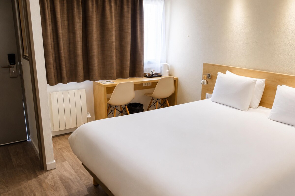 Une chambre d’hôtel avec un grand lit, un bureau, une chaise et un radiateur.