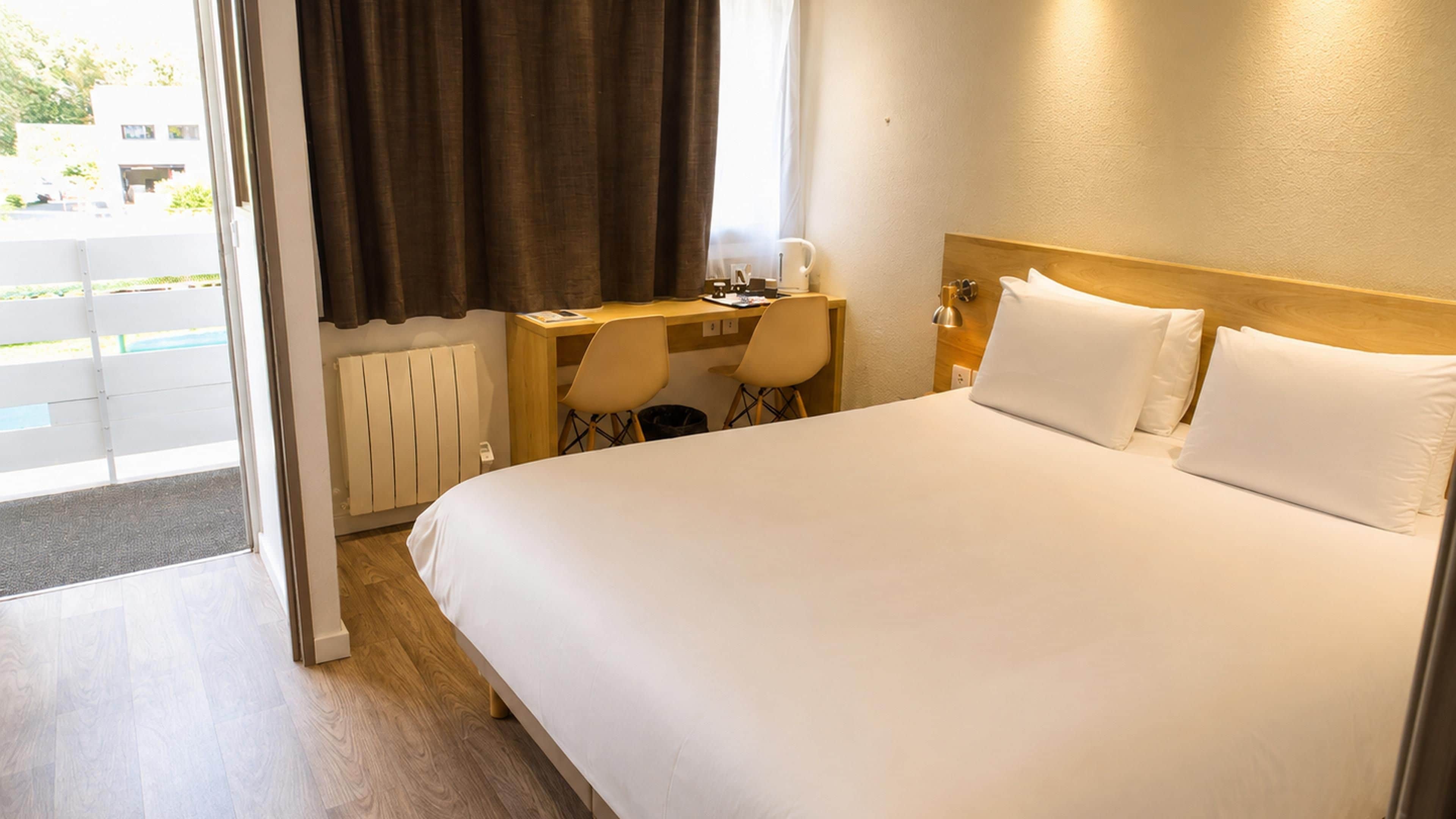Een hotelkamer met een bed, bureau en stoel.
