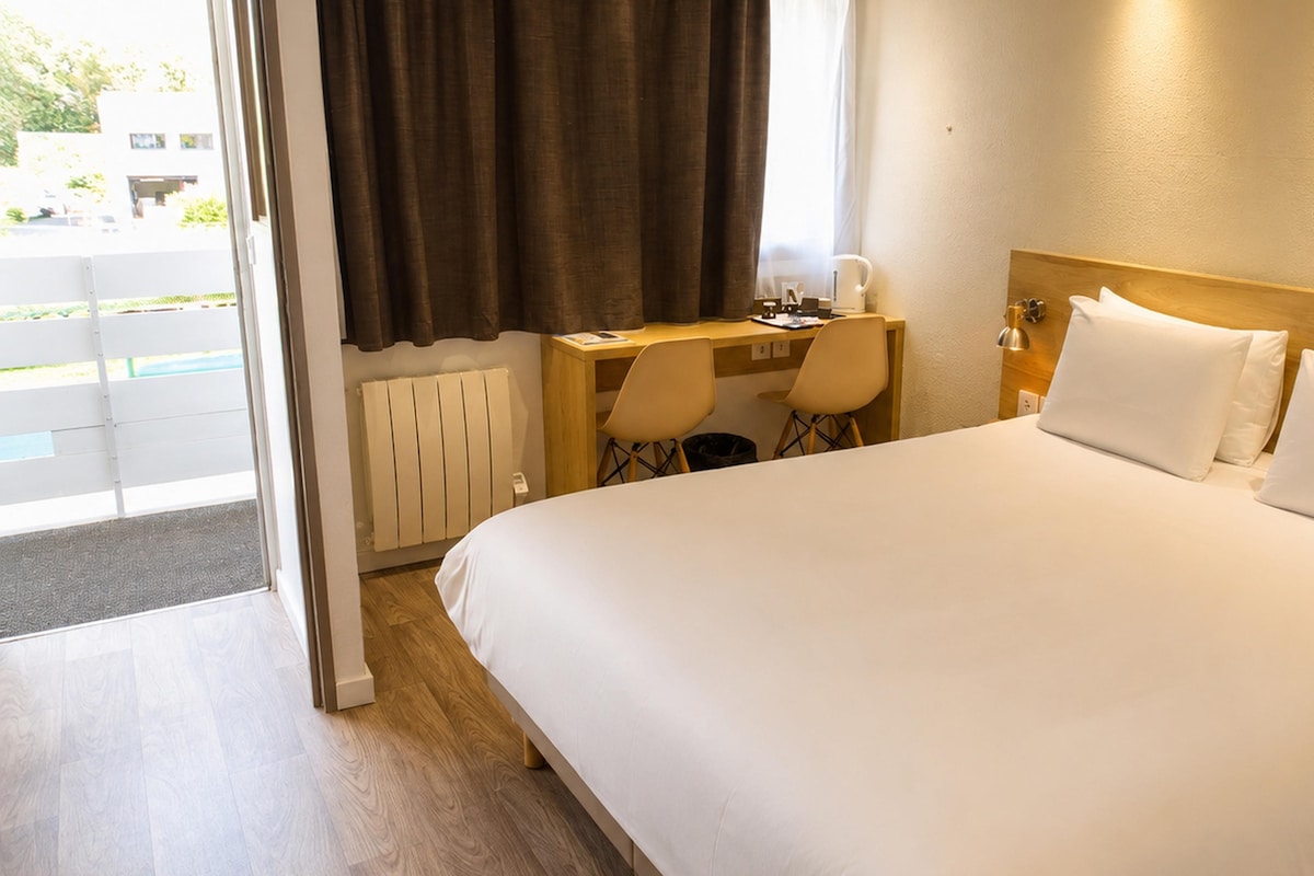 A hotel room with a bed, a desk, and a chair.