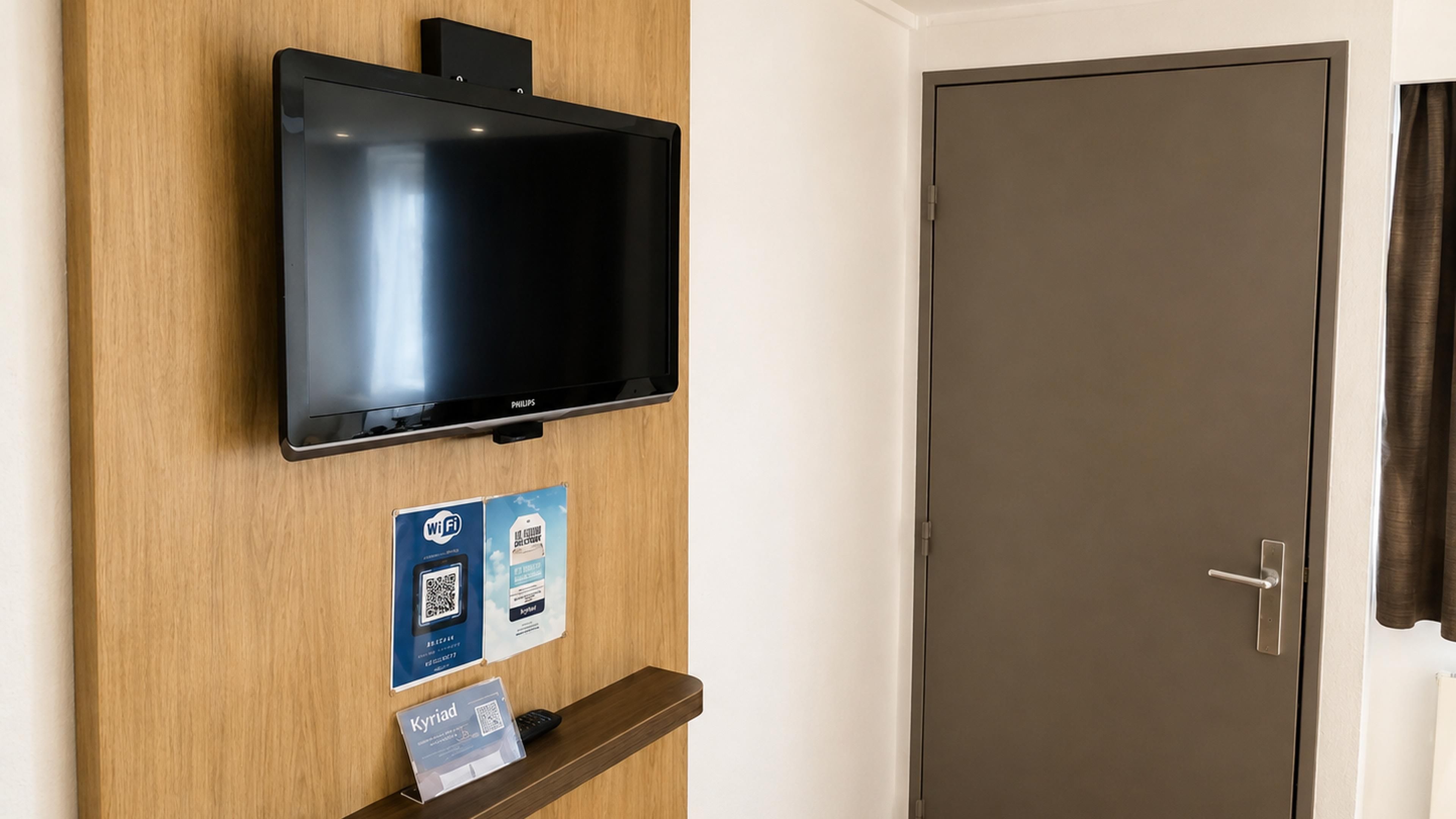 A television mounted on a wooden wall, a door, and a sign with QR codes.