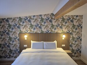Un dormitorio con una cama, dos lámparas de noche y una pared decorada con un diseño de hojas tropicales.