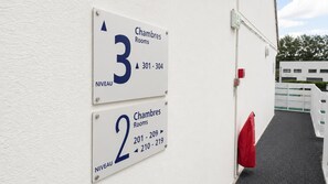 Dos carteles que indican números de habitaciones y los rangos correspondientes en la pared exterior de un edificio.
