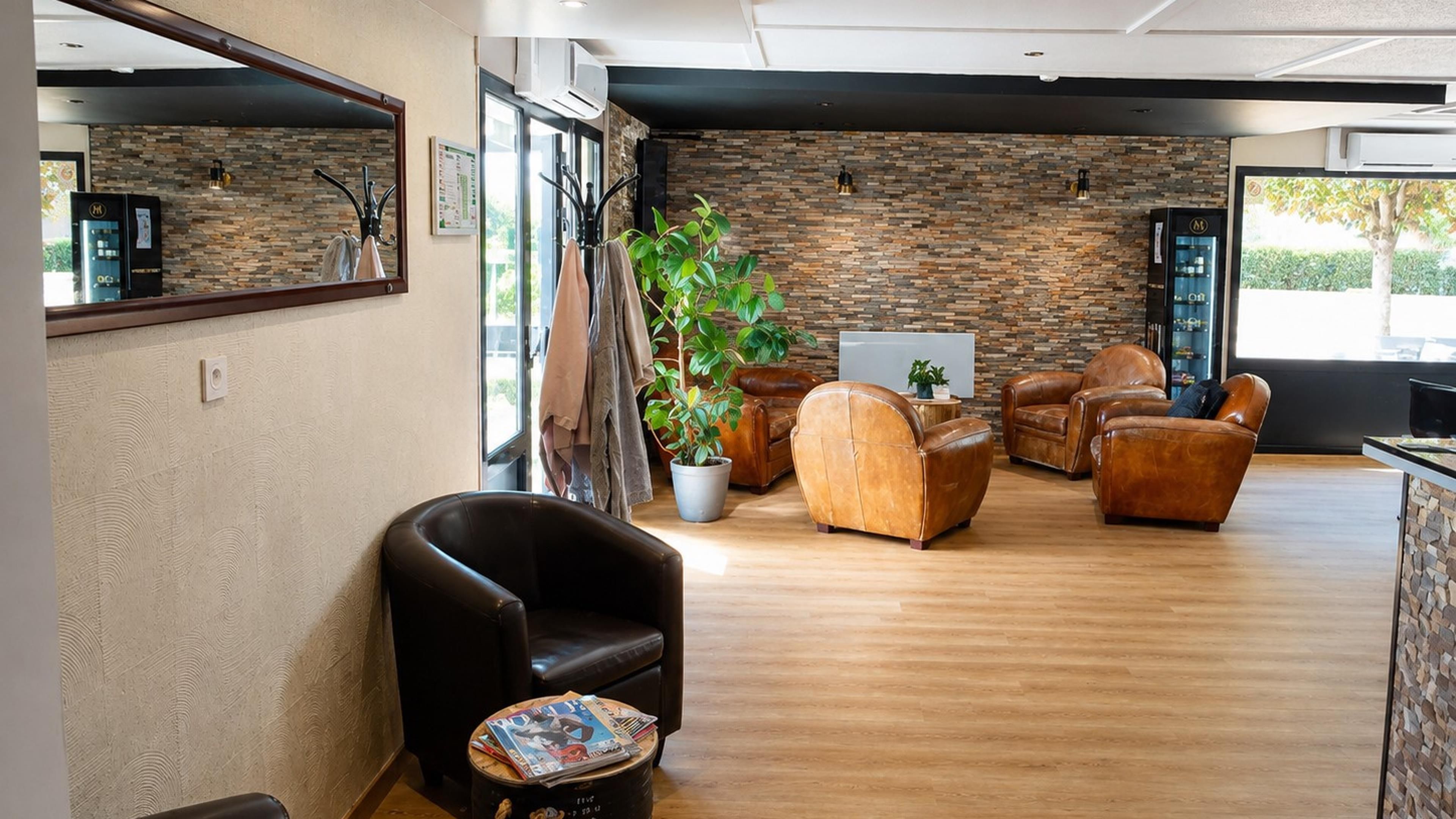 A modern lounge area with leather sofas, a coffee table, and a potted plant.