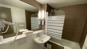 Une salle de bain moderne équipée d’un lavabo, d’un miroir et d’un sèche-cheveux.