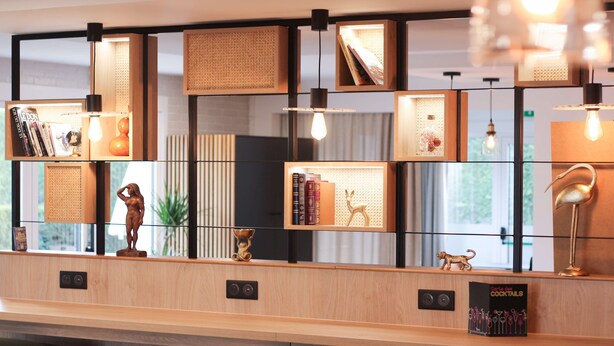 A reception desk with a wooden finish, multiple shelves with books and decorative items, and pendant lighting.
