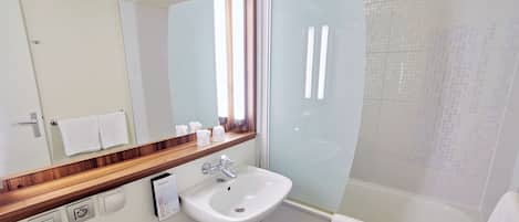 Un baño moderno con un lavamanos blanco, un espejo con marco de madera, una cabina de ducha y una bañera.