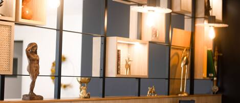 Un interior moderno con mostrador de madera, objetos decorativos e iluminación en la pared.