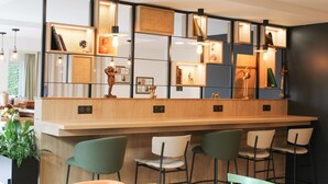 A modern bar area with a wooden counter, multiple bar stools, and pendant lighting.