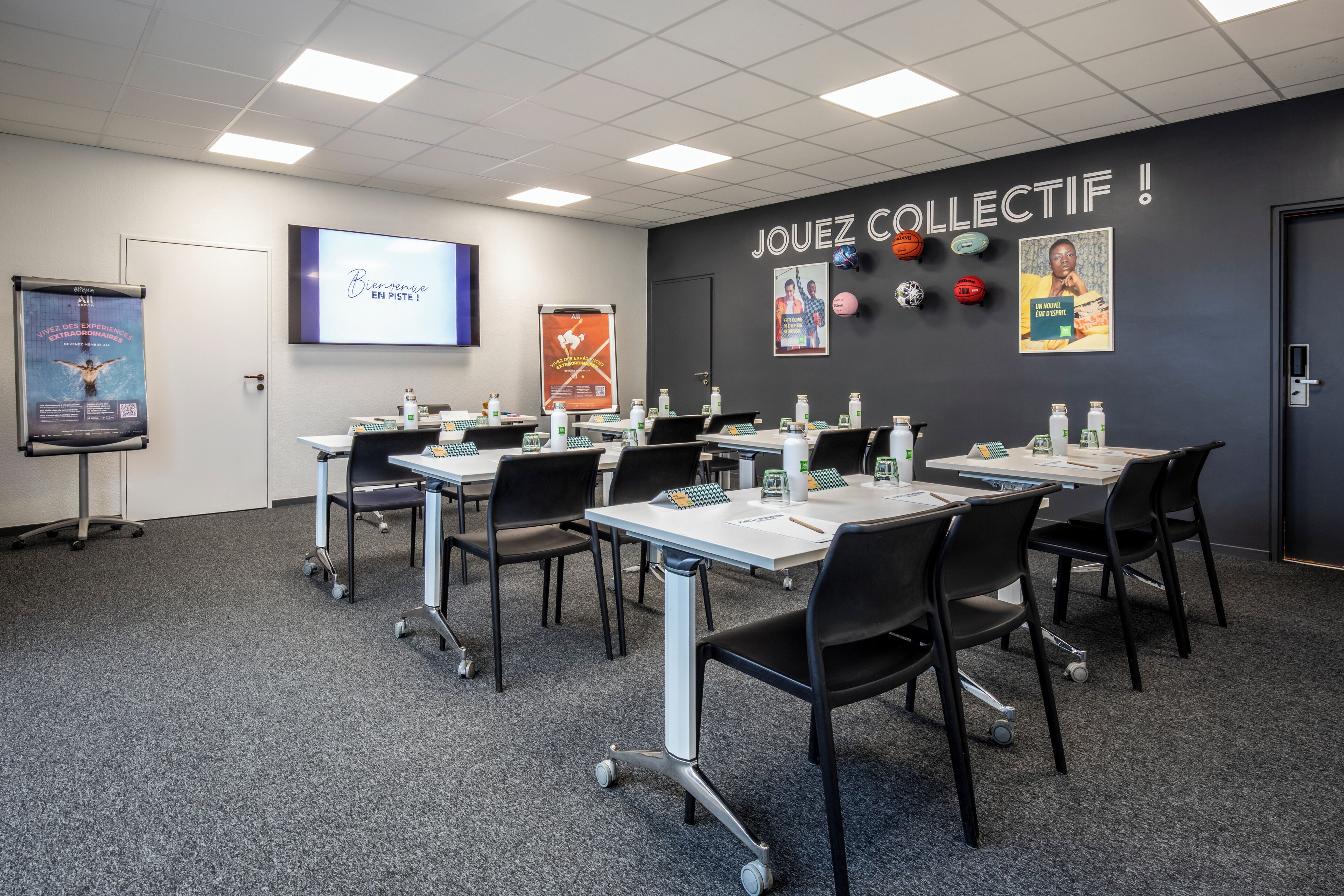 A conference room with tables, chairs, and presentation screens.