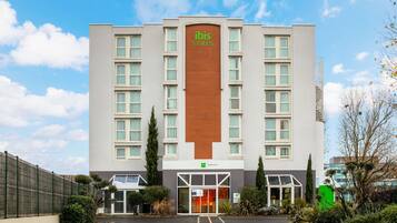 Un hotel con un evidente cartello 'ibis Styles', un parcheggio e un ingresso recintato.