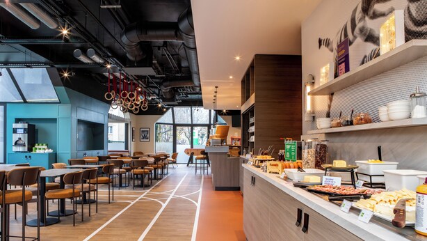 Un restaurante moderno con una barra alargada, varias zonas de estar y vistas al exterior.