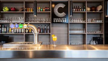Een bar met een tappunt, flessen op planken, glazen en een bordje met de tekst 'CHARLIE'S CORNER'.