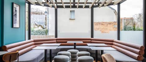 A modern interior with a long table, cushioned seating, and round ottomans.