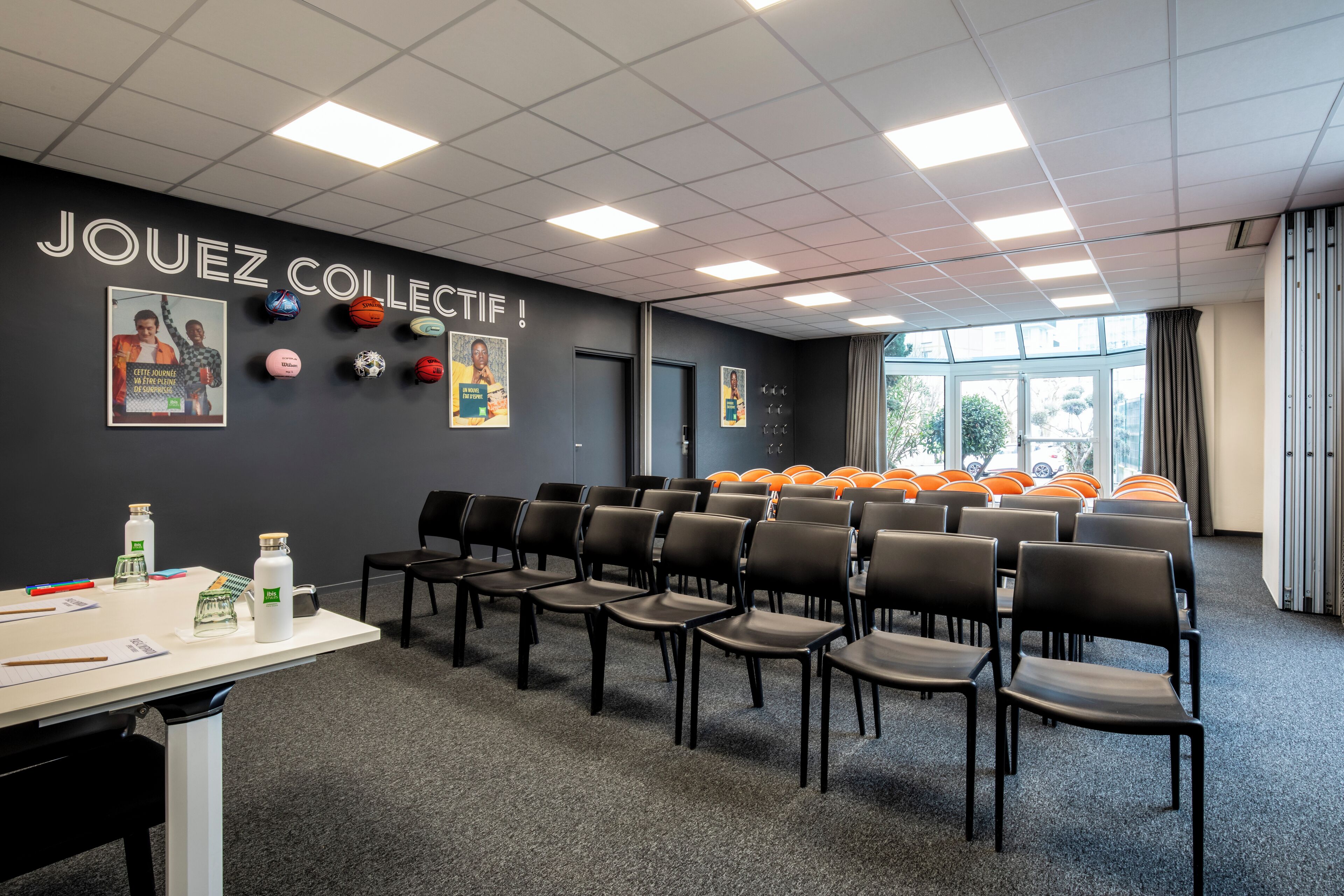 A conference room with a black wall, multiple posters, and a row of chairs.