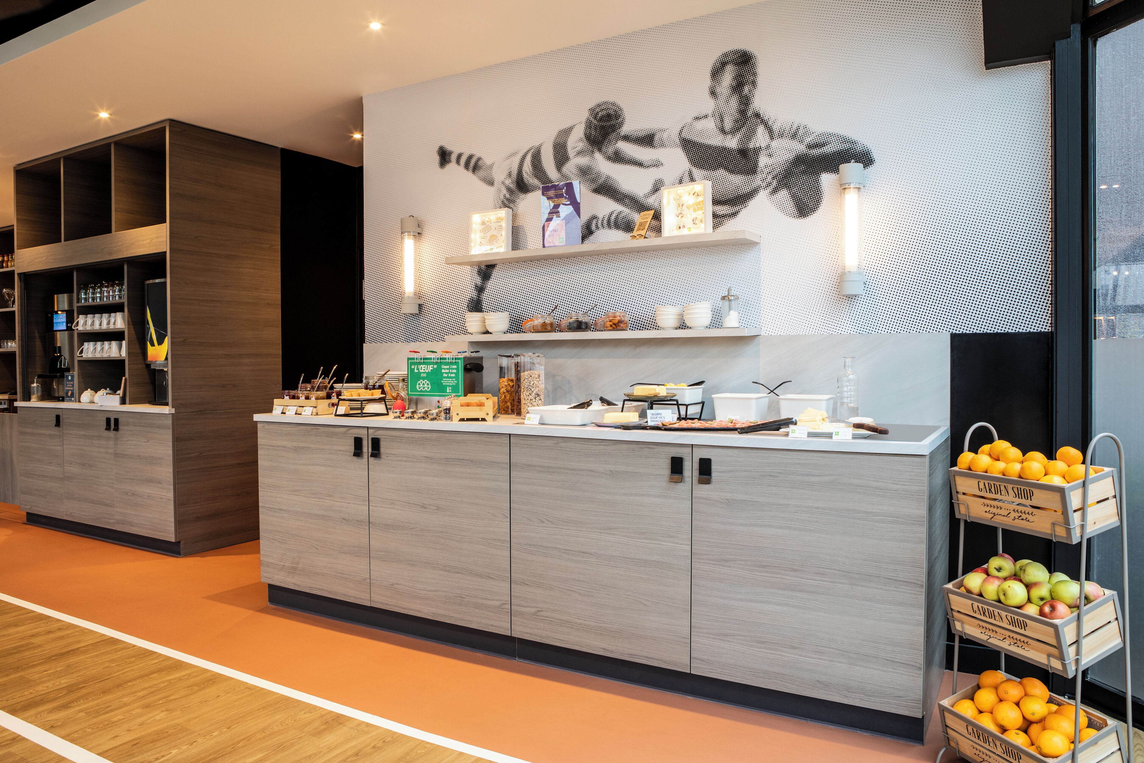 A modern kitchen area with wooden cabinets, a countertop with various items, and a wall-mounted shelf displaying kitchenware.