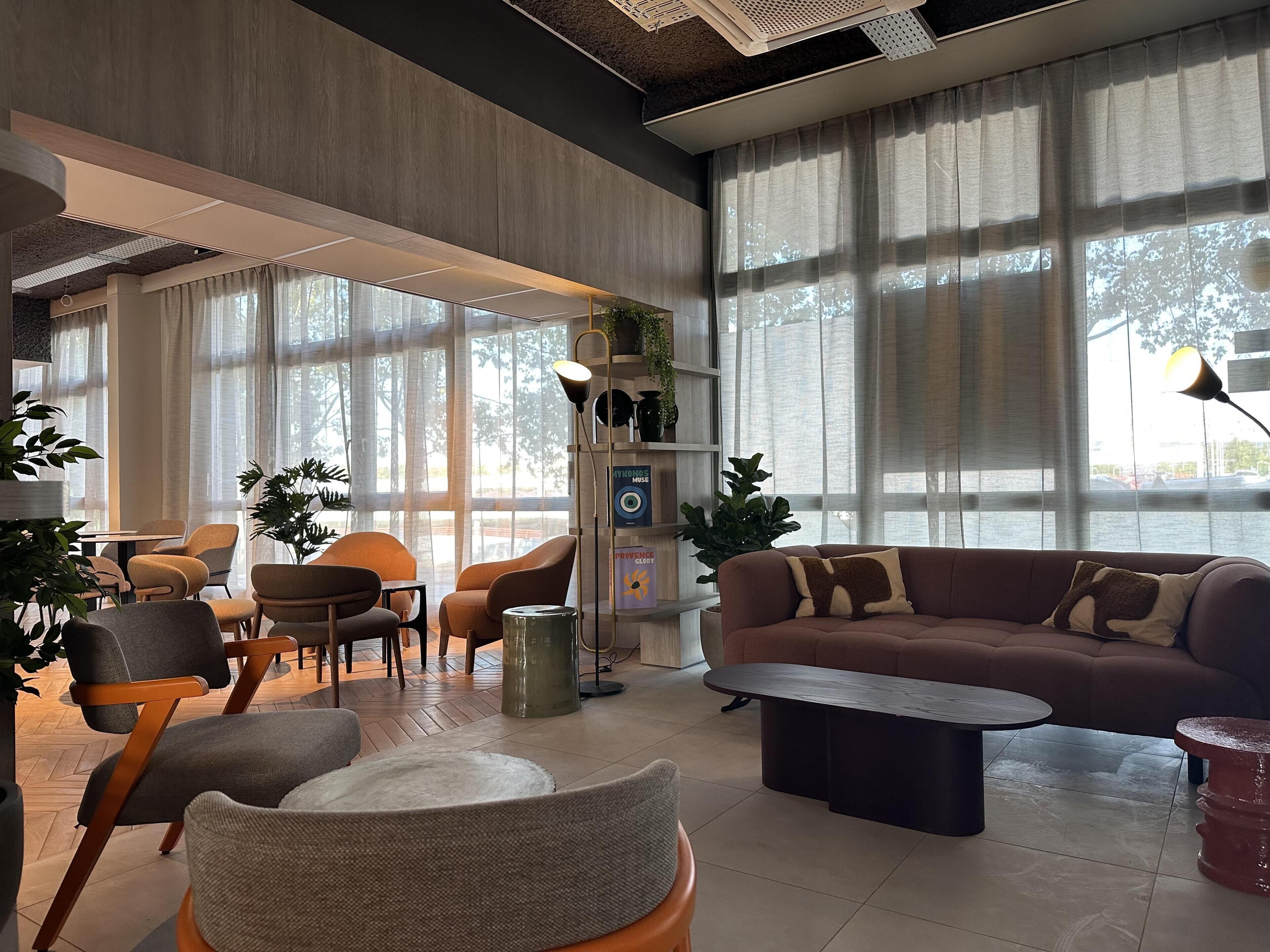 Uma sala de estar moderna com sofá, poltronas, mesa de centro e janelas amplas.