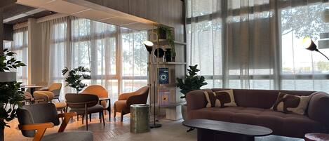Una sala moderna con sofá, sillones, una mesa de centro y ventanas amplias.