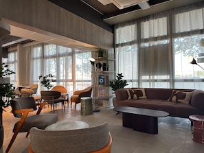Ein stilvolles Wohnzimmer mit einer Couch, Sesseln, einem Couchtisch und großen Fenstern.