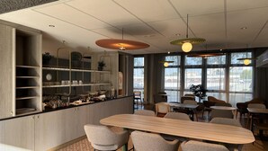 Un interior moderno con una zona de bar, asientos y ventanas amplias.