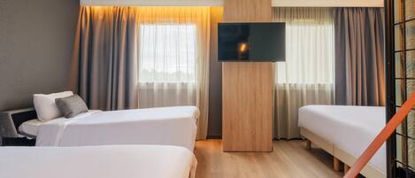 A hotel room with two beds, a flat-screen TV, and a wooden accent wall.