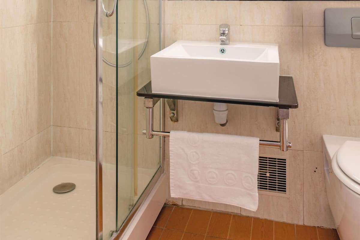 A modern bathroom with a glass shower enclosure, a white sink, and a mirror above it.